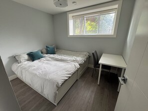 Un dormitorio con cama, escritorio y ventana.