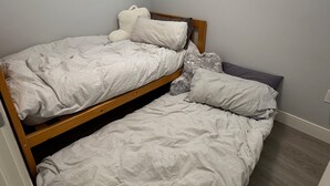 Ein Einzelbett mit Holzrahmen und Kopfteil, ausgestattet mit Kissen und Decke.