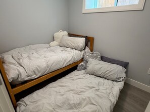A single bed with a wooden frame and a headboard, accompanied by a pillow and a blanket. - 2BR Modern Suite - 20 mins to Downtown (Vancouver)