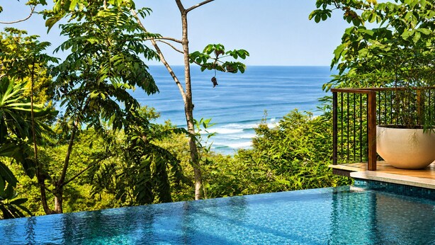 Ein Pool mit Blick auf den Ozean, umgeben von üppiger Vegetation.