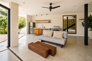 Un espace de vie moderne comprenant un canapé, une table basse et un coin cuisine avec un barbecue.