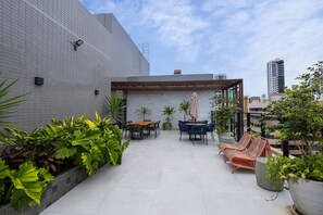 Eine Dachterrasse mit Pergola, Sitzgelegenheiten und Topfpflanzen.