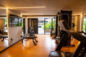 Ein modernes Fitnessstudio mit Trainingsgeräten, großen Spiegeln und Blick ins Freie.