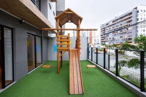 A rooftop playground with a wooden climbing structure, green artificial turf, and a view of the cityscape. - Unigreen Residence Manaira by Carpediem Close to the Beach, Manaira Shopping and MAG Shopping (João Pessoa)
