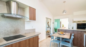 A modern kitchen with a built-in stove, wooden cabinets, and a glass-fronted range hood. - Casa em Garopaba com Churrasqueira e Hidro (Garopaba)