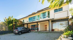 A two-story building with a car parked in front, a large window, and a signboard. - Casa em Garopaba com Churrasqueira e Hidro (Garopaba)