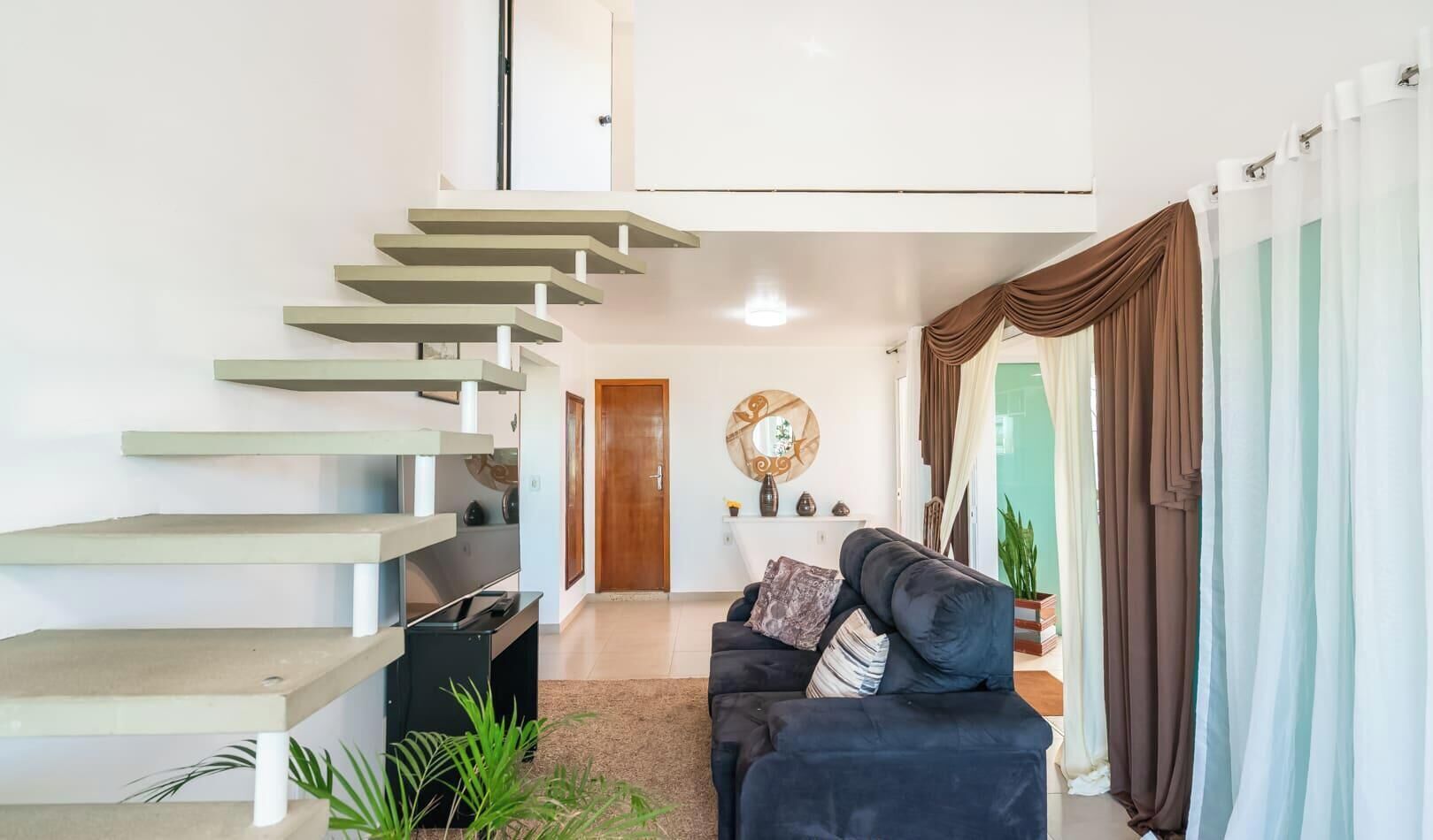 Un interior moderno con una escalera, un sofá y un espejo.