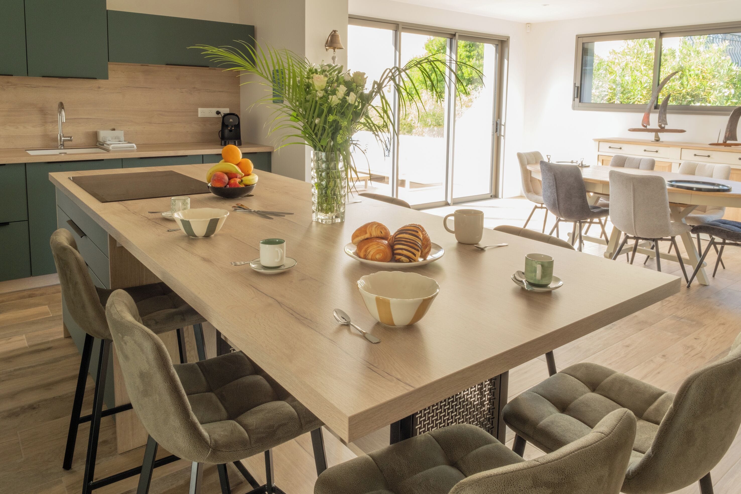 Une cuisine moderne dotée d’un îlot central, de tabourets de bar et d’un coin repas avec des chaises.