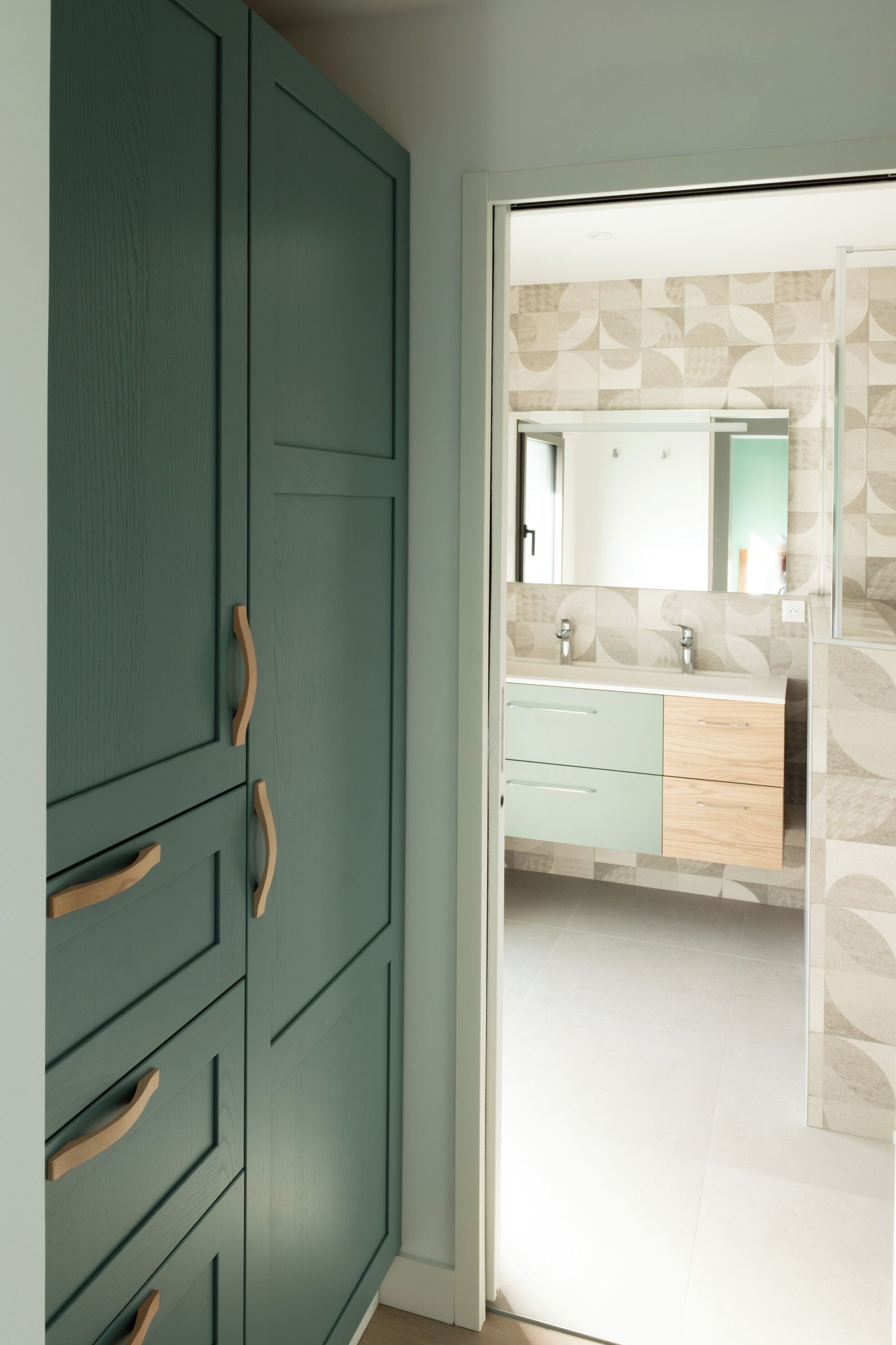 A room with a wardrobe, a bathroom with a mirror, and a tiled floor.
