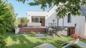 A modern outdoor living area with a hot tub, a seating area with a sofa and chairs, and a staircase leading to a covered patio. - Stunning, Renovated Family Villa in Le Pouliguen (Le Pouliguen)
