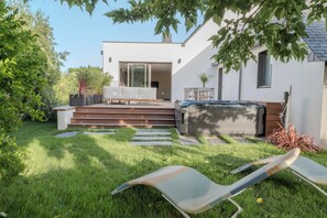 A modern outdoor living area with a hot tub, a seating area with a sofa and chairs, and a staircase leading to a covered patio. - Stunning, Renovated Family Villa in Le Pouliguen (Le Pouliguen)