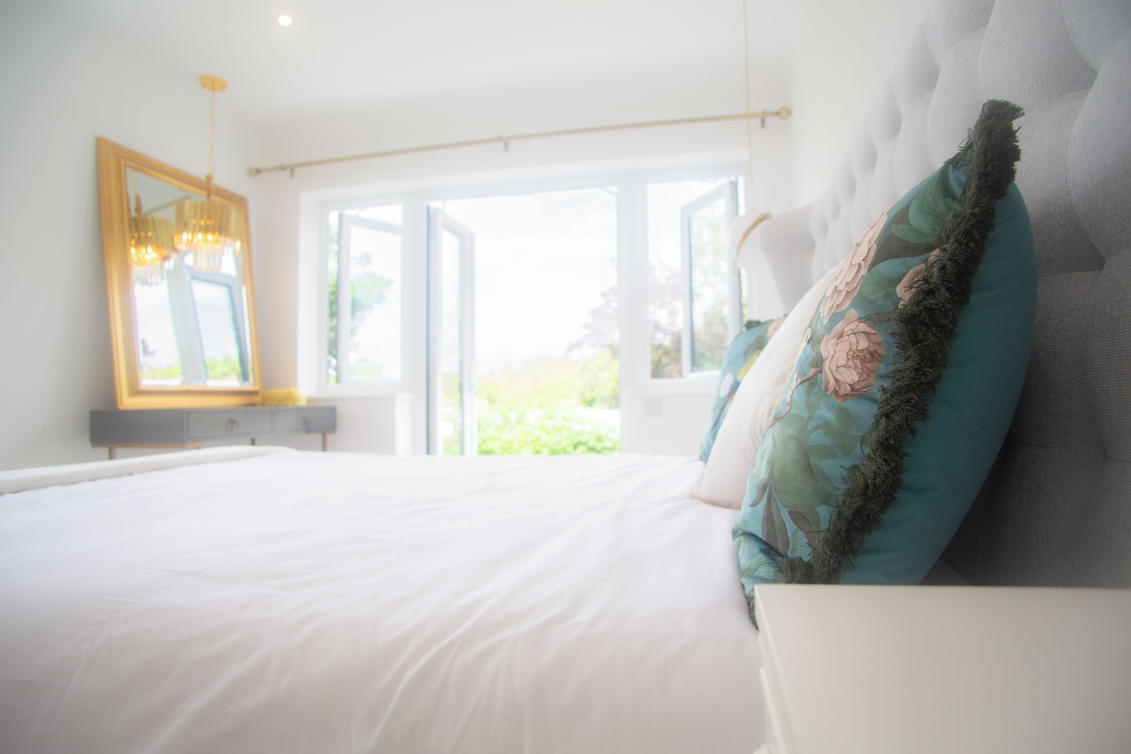 Un dormitorio con una cama grande, un espejo y vistas al exterior.