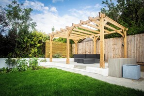 Une structure de pergola en bois dotée d’un espace salon intégré.