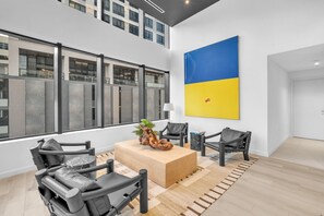 A modern interior with a large window, a wooden coffee table, and two black chairs. - Dazzling 2BR Miami | Rooftop Pool & Co-Working (Miami)