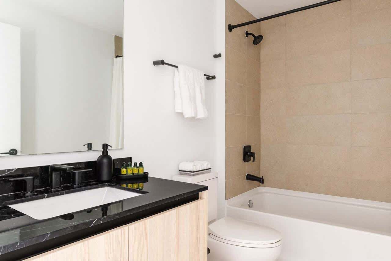 A modern bathroom with a black countertop, white sink, and a white toilet.