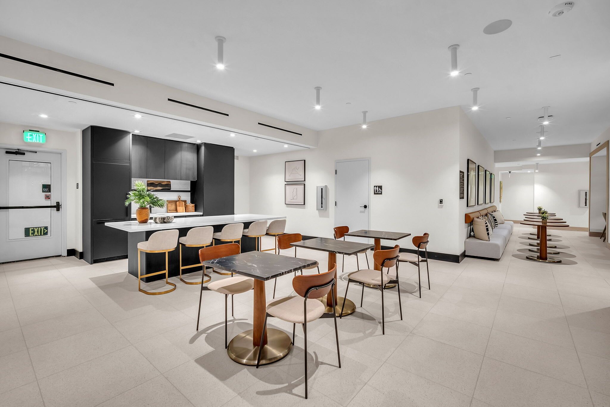 A modern hotel lobby with a central dining area, a kitchen, and a seating area with a sofa and coffee table.