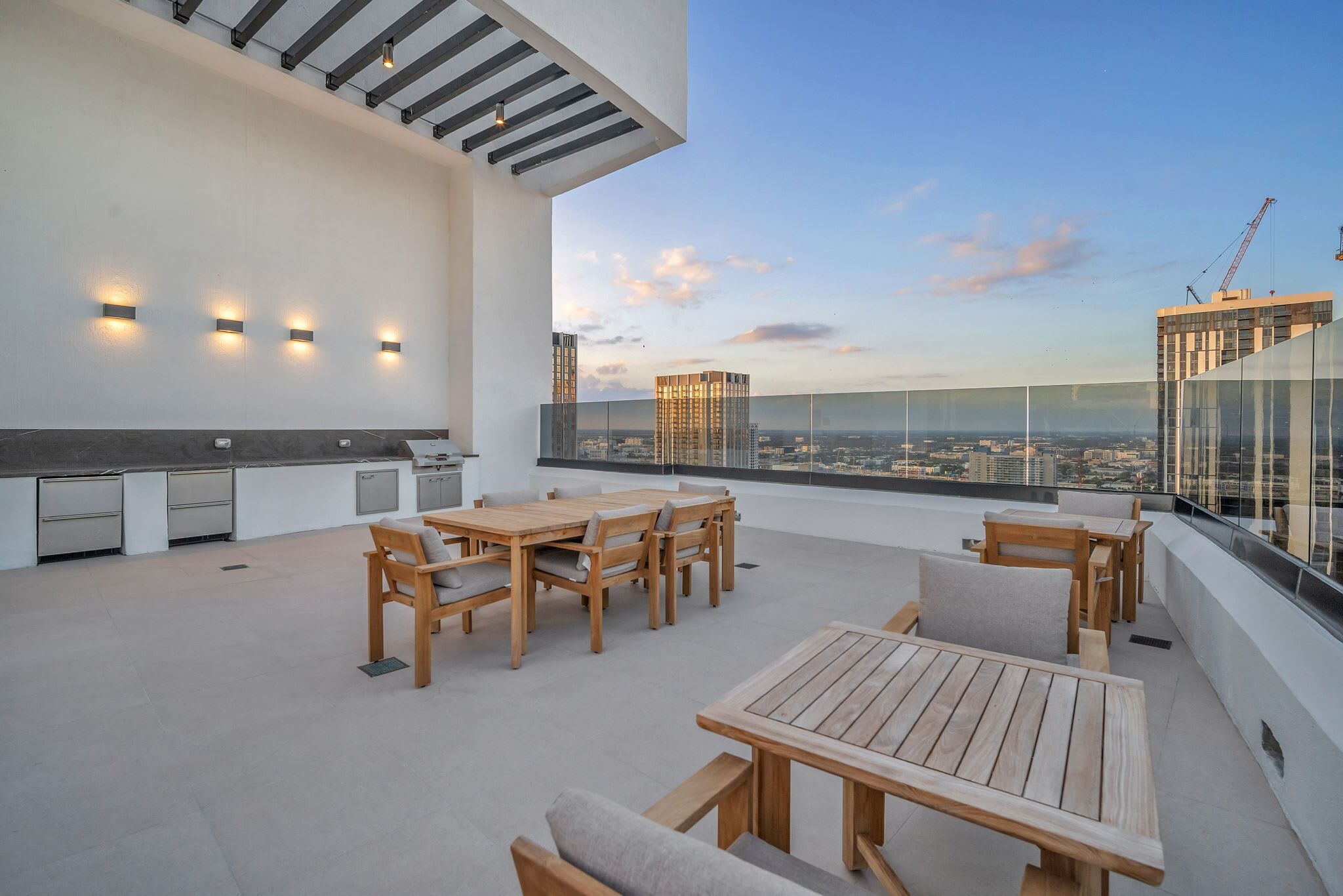 A rooftop terrace with a dining area, outdoor kitchen, and city views.