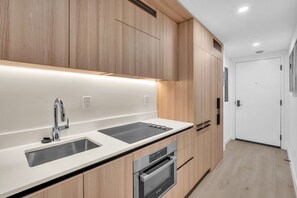 A modern kitchen with wooden cabinets, a stainless steel sink, and an oven. - Dazzling 2BR Miami | Rooftop Pool & Co-Working (Miami)
