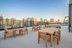 A rooftop terrace with wooden furniture and a city view. - Dazzling 2BR Miami | Rooftop Pool & Co-Working (Miami)