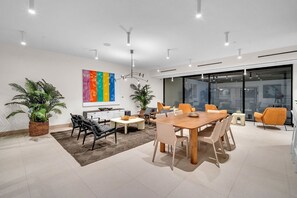 A modern office space with a large meeting table, comfortable seating, and potted plants. - Modern 2BR Miami | Rooftop Pool | Near Bayfront (Miami)
