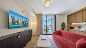 En moderne stue med et fladskærms-TV, en rød sofa, et sofabord og en tæppe med et mønster.