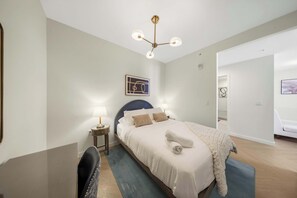 Ein Hotelzimmer mit Bett, Nachttischen, Schreibtisch, Stuhl, Deckenleuchte und einem Bild an der Wand.
