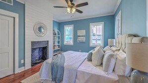 A bedroom with a bed, a ceiling fan, a fireplace, and a window. - 1880s Charleston Single, Two bedroom with parking (Charleston)