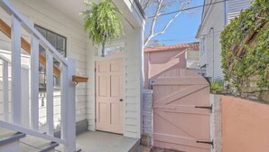 A white house with a pink gate, a wooden staircase, and a brick pathway. - 1880s Charleston Single, Two bedroom with parking (Charleston)