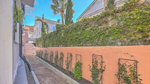 A narrow pathway flanked by a wall with climbing plants and a brick-paved area. - 1880s Charleston Single, Two bedroom with parking (Charleston)