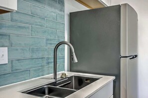 A kitchen with a stainless steel sink, a modern faucet, and teal blue tiles on the backsplash. - 1880s Charleston Single, Two bedroom with parking (Charleston)