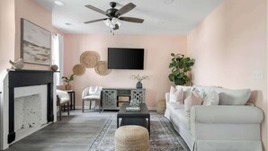 A living room with a fireplace, a sofa, a coffee table, and a television. - 1880s Charleston Single. Bermuda Suite one bedroom (Charleston)