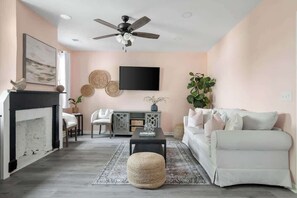 A living room with a fireplace, a sofa, a coffee table, and a television. - 1880s Charleston Single. Bermuda Suite one bedroom (Charleston)