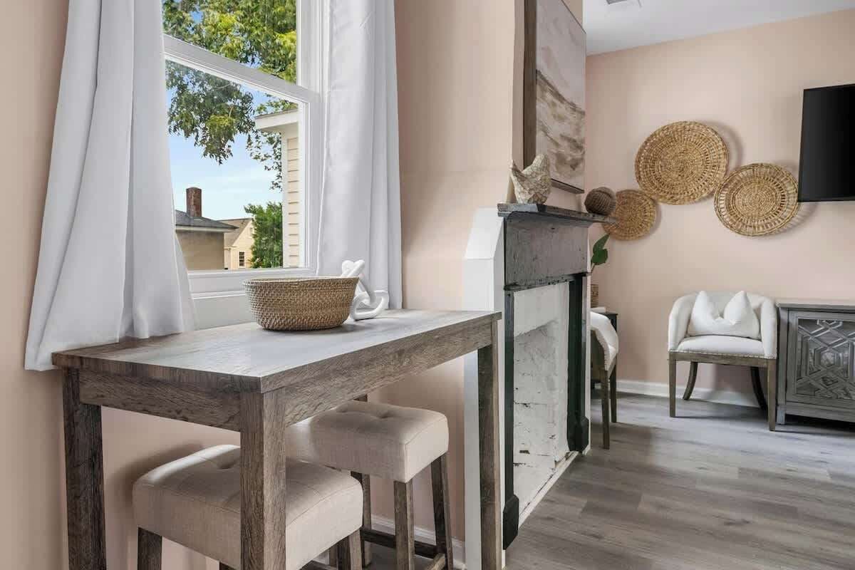 A dining area with a wooden table, white chairs, a basket, and a television on the wall.