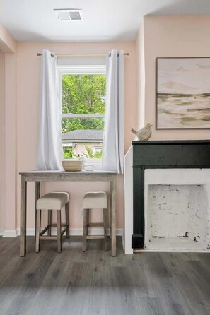 A room with a window, a table with chairs, and a fireplace. - 1880s Charleston Single. Bermuda Suite one bedroom (Charleston)