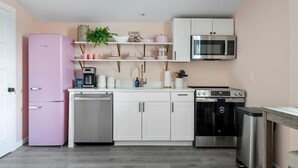 A compact kitchen with a pink refrigerator, white cabinets, a microwave, an oven, and a dishwasher. - 1880s Charleston Single. Bermuda Suite one bedroom (Charleston)