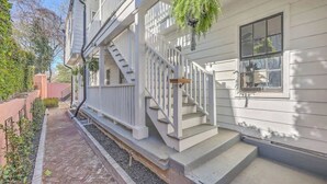 A white house with a front porch, a staircase, and a hanging planter. - 1880's Charleston Single. One Bedroom with parking (Charleston)