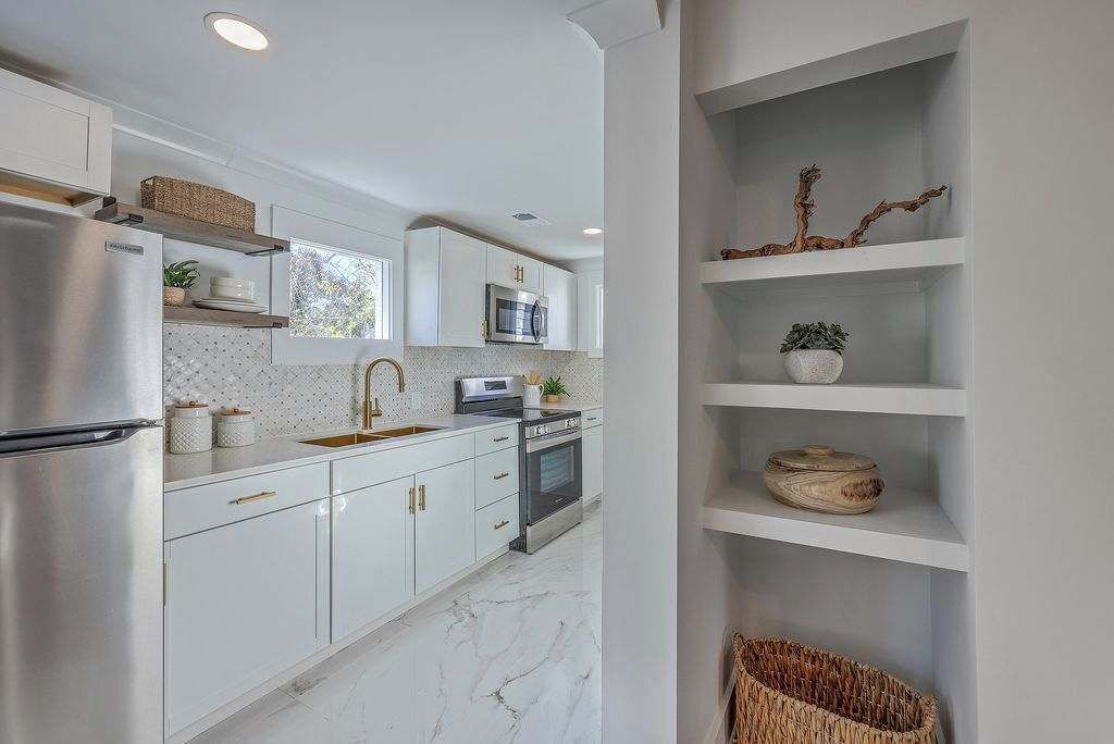 A modern kitchen with white cabinetry, a stainless steel refrigerator, a microwave, and a built-in oven.
