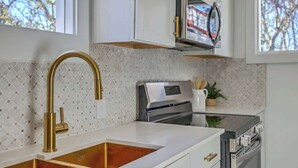 A modern kitchen with a gold faucet, white cabinets, and a stainless steel oven. - 1880's Charleston Single. One Bedroom with parking (Charleston)