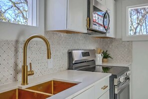 Eine moderne Küche mit goldenem Wasserhahn, weißen Schränken und einem Edelstahlbackofen.