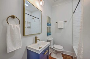 Ein Badezimmer mit weißem Waschbecken, Toilette, einer Dusche mit Glastür und einem Handtuchhalter.