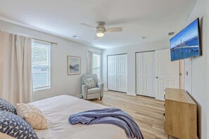 A bedroom with a bed, a chair, a ceiling fan, and a TV mounted on the wall. - Pilgrim Luxury #3. Newly Built! (Hanahan)