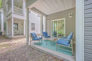 A covered porch with four blue chairs and a small table, a second-story balcony, and a sliding glass door to the right. - Pilgrim Luxury #3. Newly Built! (Hanahan)