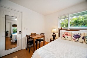 Ein Schlafzimmer mit einem Bett, einem Schreibtisch, einem Stuhl, einer Lampe und einem Fenster mit Jalousien.
