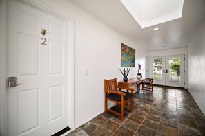 A hallway with a white door marked '2', a wooden bench, a small table with a vase, and a colorful painting on the wall. - Double Studio Suites with Private Pool and AC, walk to Beach (Koloa)