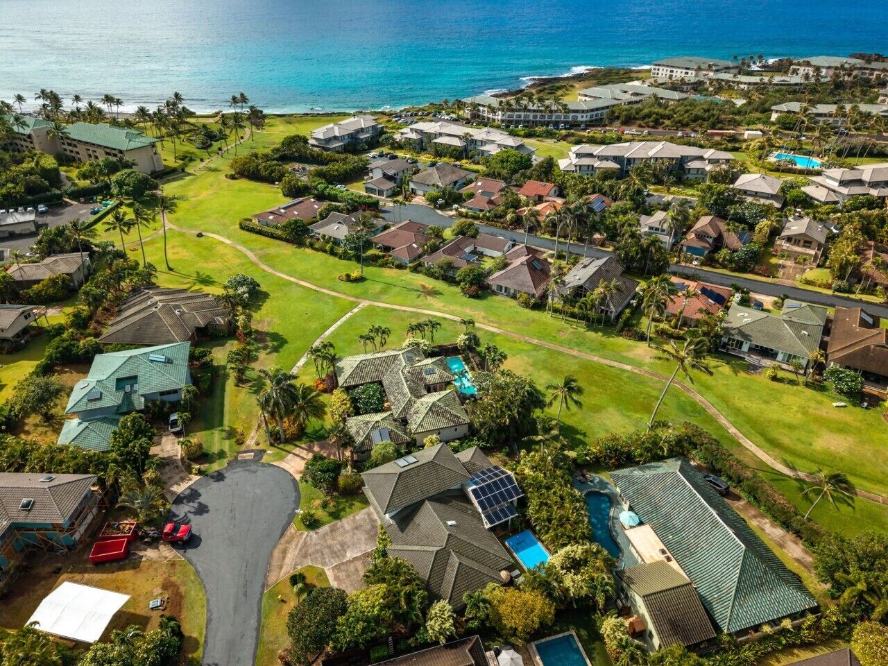 An aerial view of a residential area with houses, a golf course, and a swimming pool.