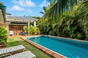 A swimming pool with a wooden deck, lounge chairs, and lush tropical vegetation. - Double Studio Suites with Private Pool and AC, walk to Beach (Koloa)