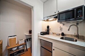 Eine kompakte Küche mit Mikrowelle, Toaster und Kaffeemaschine.
