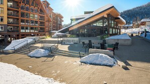 Ein modernes Gebäude mit großen Fenstern, einem geneigten Dach und einer mit Ziegeln gepflasterten Fläche mit Schnee.