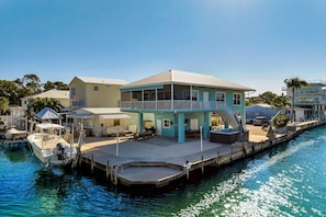 Ein Anwesen am Wasser mit Anlegesteg, überdachter Terrasse und Schwimmbad.