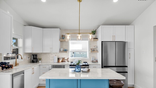 A modern kitchen with white cabinets, a stainless steel refrigerator, a central island with stools, and pendant lighting. - Waterfront Hideaway · 100-Ft Dock · Hot Tub with TV — Your Keys Escape (Key Largo)